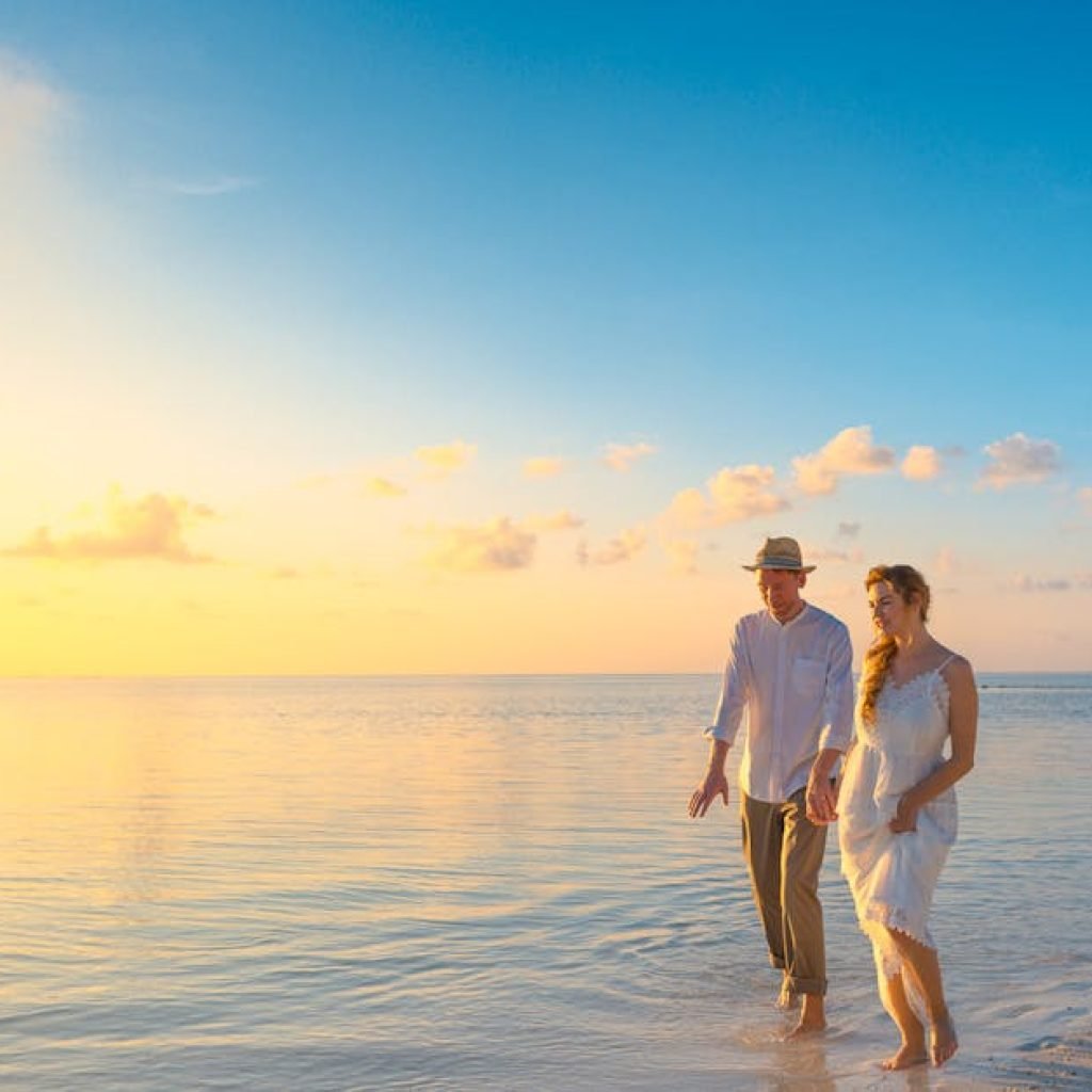 A couple enjoys a romantic walk on a sunny beach in the Maldives at sunrise.